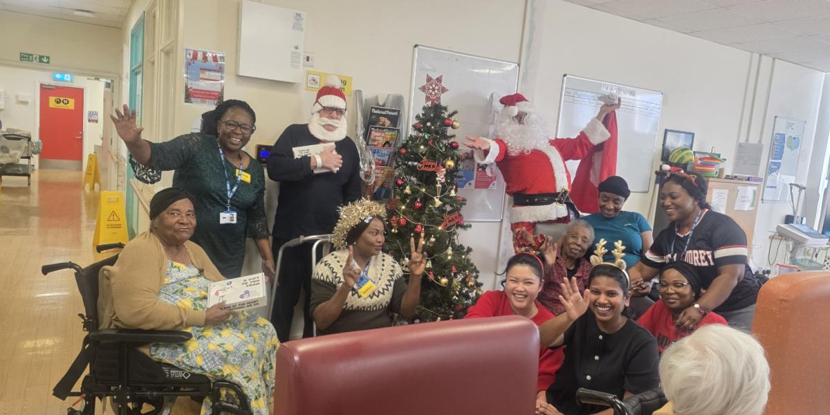 Patients and CNWL staff at St Pancras Hospital smiling and waving with their wellbeing boxes on Christmas Day