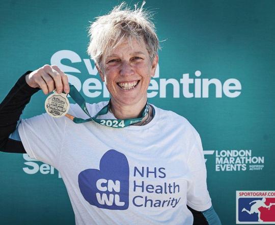 CNWL NHS Health Charity swim serpentine supporter. She is wearing a white t-shirt, smiling and holding her medal