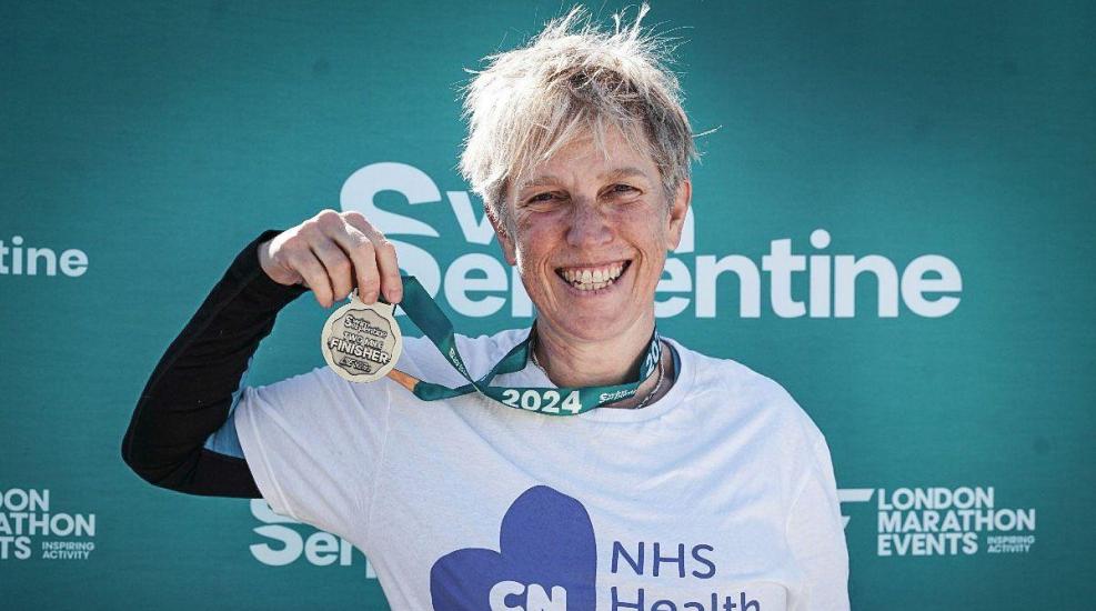 CNWL NHS Health Charity swim serpentine supporter. She is wearing a white t-shirt, smiling and holding her medal